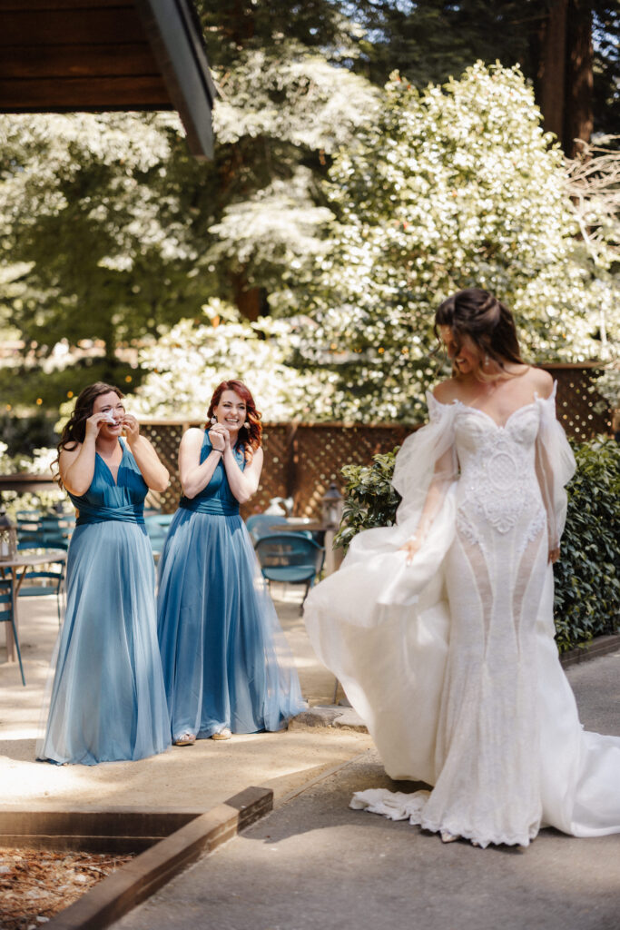 Two bridesmaids reacting with joy and tears as they see the bride for the first time before the ceremony, documentary photography by Honey & Bloom