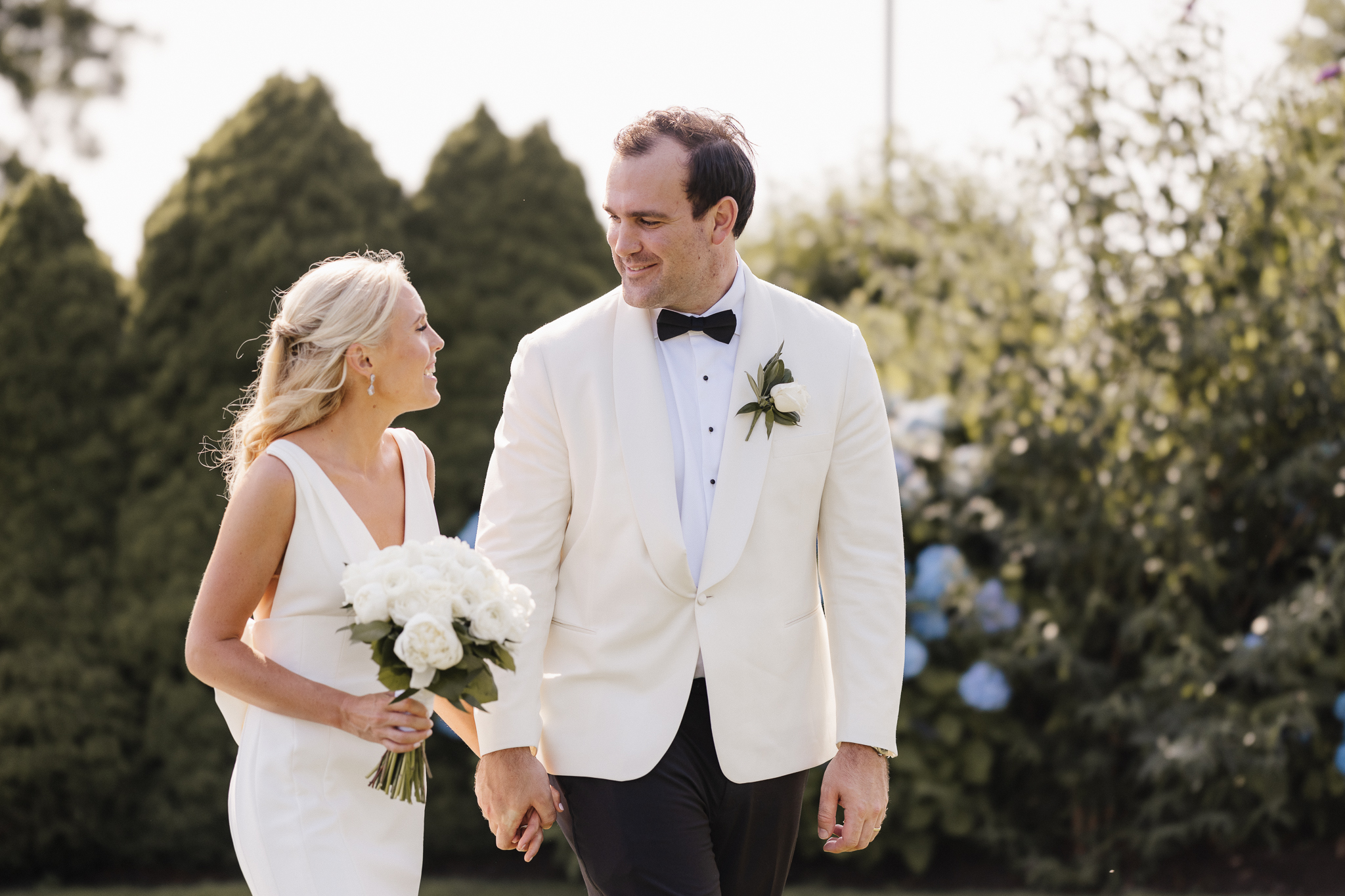 Couple walking together through a garden before their outdoor elopement in Central New York, Honey and Bloom Photography.