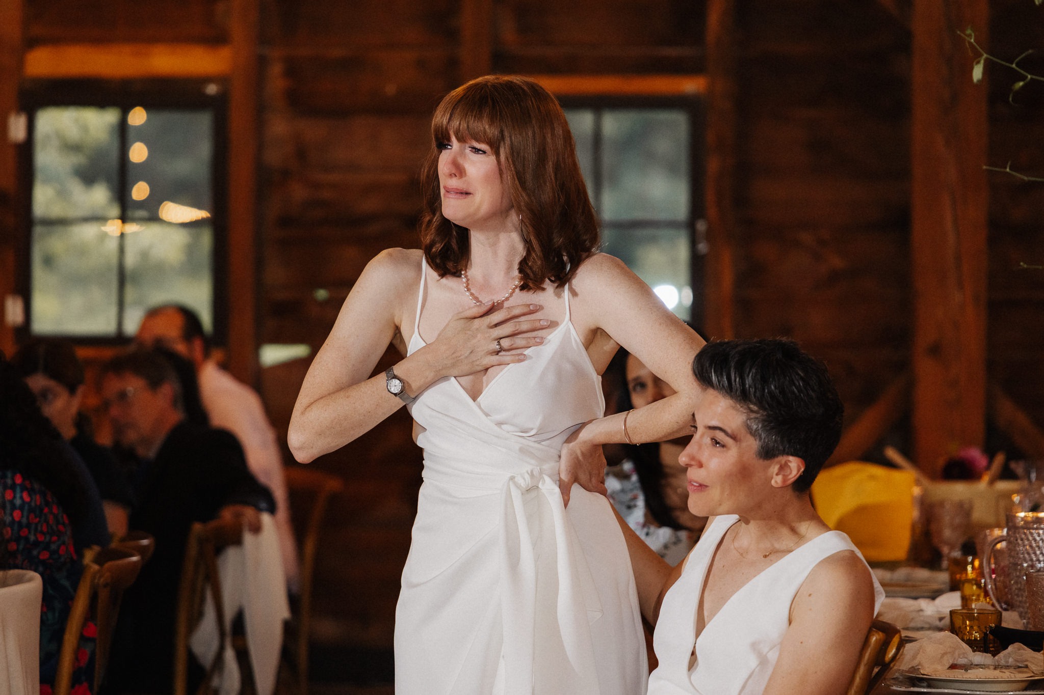 Two brides sharing an emotional moment during their wedding reception.