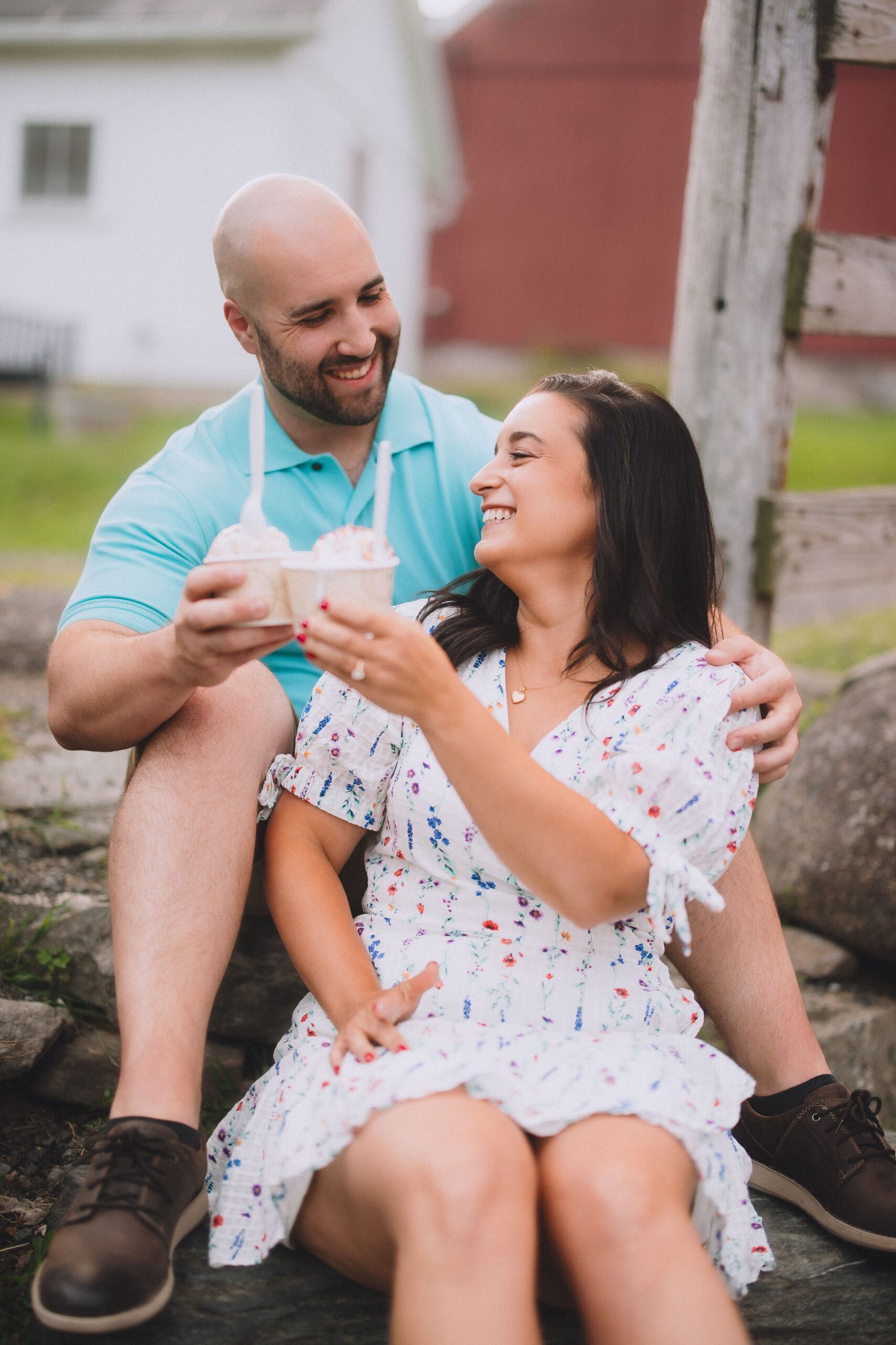 Engaged couple laughing together while sharing milkshakes during their Central New York engagement session.