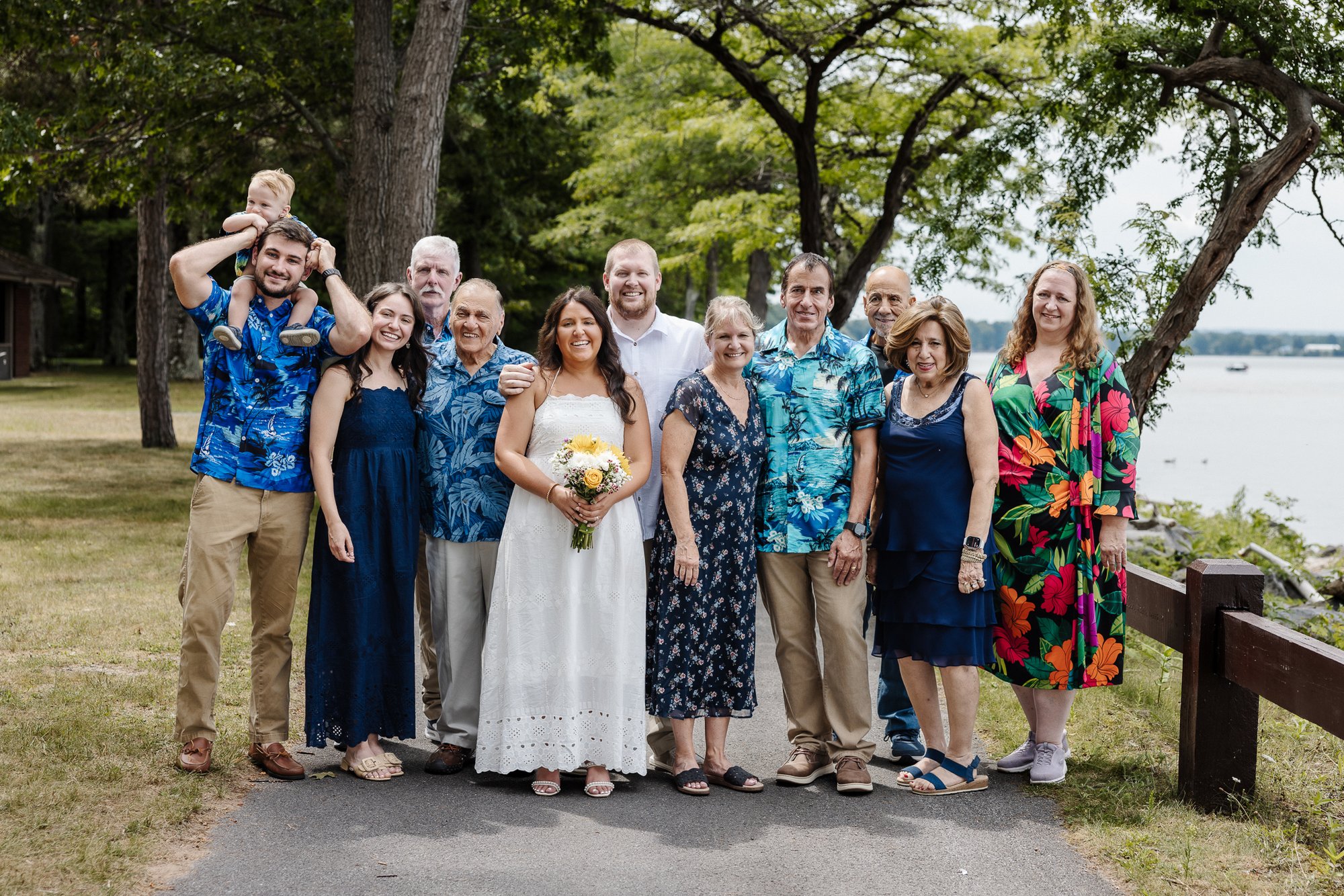 Family in Hawaiian shirts on the shaded lakeside path at Verona Beach State Park, a toddler up on someone's shoulders, Honey and Bloom Photography